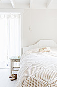 Lacy blanket on bed in bright bedroom decorated entirely in white