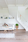 Sofa below staircase in simple living room decorated entirely in white