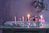 Lit candles behind festive paper doll chain moulded from concrete