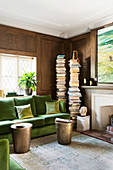 Green velvet sofa in the paneled living room with an open fireplace