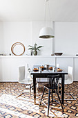 Dunkler Esstisch mit Designerstühlen vor weißer Wand