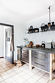 Schubladenschränke mit Betonplatte und schwarze Wandregale in der Küche