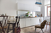 White kitchen counter, upholstered chair and bistro table with barstools in kitchen