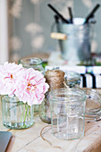 Preserving jars and pink flowers on wooden table