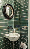 Green wall tiles, marble sink and mirror in guest toilet