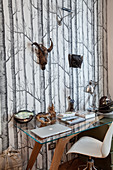 Desk with glass top and designer chair against tree-patterned photo wallpaper