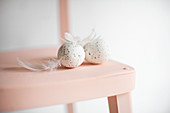 Speckled eggs and feathers on pink chair