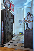 Cabinet with structured front and collection of sculptures in foyer