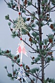 Garland of paper Christmas trees hung from larch branch