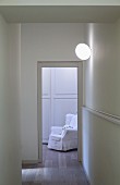 White armchair seen through open door in hallway