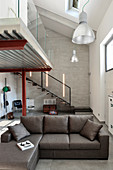 Grey couch in industrial loft apartment with gallery