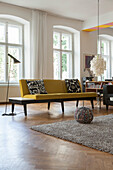 Yellow sofa and standard lamp in front of window in period apartment