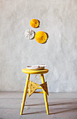 Paper rosettes on wall above yellow stool with bunting