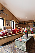 Flag-patterned scatter cushions on solid wooden corner bench in converted barn with wood-clad walls
