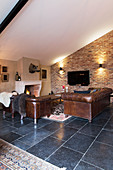 Vintage leather couch, armchair and coffee table in front of fireplace in converted barn