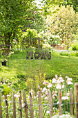 Blick über Zaun in sommerlichen Garten mit Wiese und dem Wort 'Moin' aus Holzbuchstaben