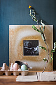 Black-and-white photo in hand-made frame, dried flowers and Easter eggs