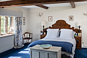 Double bed with antique wooden headboard in blue and white bedroom