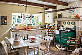 Dining table and green wood-fired stove in rustic kitchen