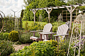 Wooden chairs in seating area in front of pergola in garden