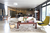 Coffee table, designer easy chair and sofa in open-plan interior