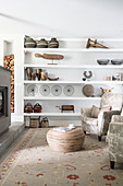 Vintage ornaments on open shelves, armchair, bamboo coffee table and log-burner in living room