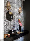 Sink on black washstand in guest toilet with patterned wall tiles