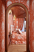 Opulent bedroom with identical orange pattern on wallpaper and fabrics