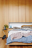 Double bed against wall with wooden paneling and alcove