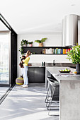 Woman and dog stand in modern kitchen with concrete island