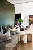 Wooden side tables and scatter cushions on sofa against wall with crocodile-effect wallpaper