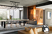 Long dining table and metal-clad wall in luxurious interior