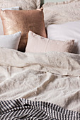 Kissen in Champagnerfarben auf dem Bett mit Leinenbettwäsche