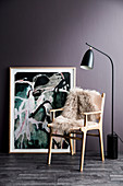 Skandinavischer Stuhl mit Schaffell vor Gemälde und violetter Wand