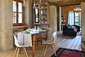 Antique dining table, classic chairs and glass-fronted cabinet in converted barn
