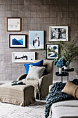 Armchairs and ottoman with linen cover in front of picture gallery on wall with designer wallpaper