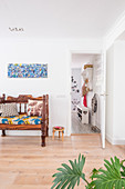 Holzbank mit bunten Kissen, darüber bunte Malerei im Wohnzimmer