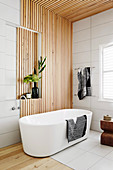 Freestanding bathtub in front of wooden paneling in the bathroom