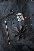 Windräder und Blume aus schwarzem Papier auf schwarzem Stoff