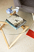 Photo book, teapot and cup on side table made of glass and wood