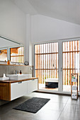 Modernes Bad mit hoher Decke und Fensterfront zum Balkon