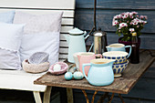 Cushions with hand-sewn covers on bench next to beakers, jugs and Easter eggs on side table