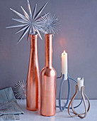 Weihnachtsdeko mit Silbersternen, kupferfarbenen Flaschen und Kerzen