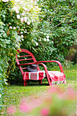Red rattan lounger in garden