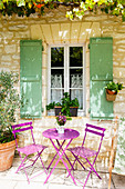 Purple garden furniture in seating area outside French stone house