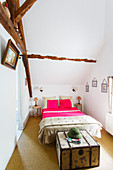 Narrow bedroom with high ceiling and old beams