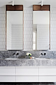 Bright bathroom with double vanity and mirror cabinets and white wall tiles