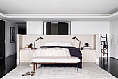Dopplebett und maßgefertigter Betthaupt mit Ablagefläche, Kleiderbank und Seidenteppich in elegantem Schlafraum