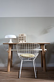 Table lamp and ceramic house on desk and classic chair in front of pale grey wall