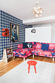 Pink gemustertes Sofa und blaue Tapete im Wohnzimmer